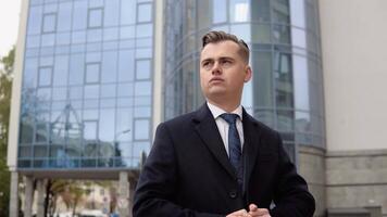 Stylish male businessman in blue jacket and coat near office center waiting for business meeting video