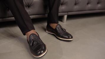 Close up of elegant man's shoes when man is sitting on a sofa video