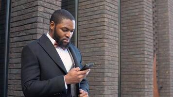 Elegant bearded african american businessman talking on phone near the office center video