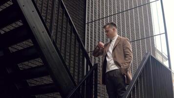 eleganta manlig affärsman i brun täcka nära kontor Centrum väntar för företag möte video