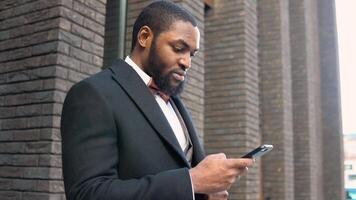 Young elegant black businessman talking on phone near the office center video