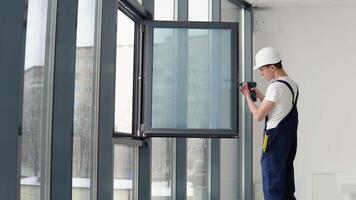 The wizard installs the screws in the window frame with a screwdriver video