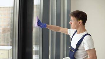 Young cleaner in protective uniform washes windows video