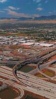 Complicated system of roads in Salt Lake City. Vast city scenery at backdrop of mountains at daytime. Top view. Vertical video