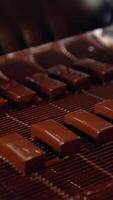 Pouring chocolate at a candy factory for the production of chocolates. Sweets are poured with chocolate on production line at a candy factory close up. Vertical video