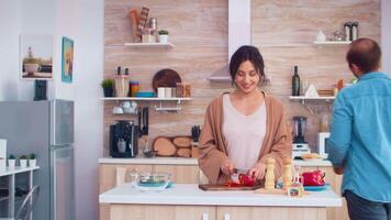 Ehefrau Hacken Glocke Pfeffer auf Schneiden Tafel und Mann öffnet Kühlschrank Tür. Kochen vorbereiten gesund organisch Essen glücklich zusammen Lebensstil. heiter Mahlzeit im Familie mit Gemüse video