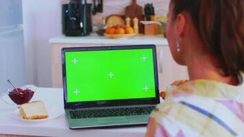 arbetssätt på läsplatta pc med grön skärm i kök under frukost. grön skärm krom falsk upp isolerat attrapp bakgrund redo till vara ersatt med din text, logotyp eller annons. använder sig av internet, social nät och bläddring video