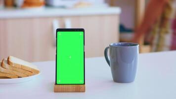 verde modello su smartphone nel cucina. casalinga al forno gustoso Cornetti per prima colazione. verde schermo croma finto su isolato modello sfondo pronto per essere sostituito con il tuo testo, logo o annuncio. utilizzando Internet, sociale reti e navigazione video