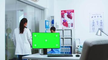 dator med grön skärm i sjukhus skåp och läkare kontroll patient röntgen. skrivbordet med utbytbar skärm i medicinsk klinik medan läkare är kontroll patient radiografi för diagnostisera. video