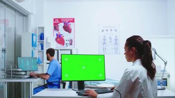 Nurse in blue uniform leaving hospital cabinet and doctor using computer with replaceable display. Computer with repleceable screen used by medicine specialist in hospital and wearing uniform. video