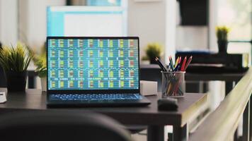 Company documents and laptop in financial department office showing stock exchange values. Business files on desk next to notebook showing forex trading indexes prices, handheld camera shot video