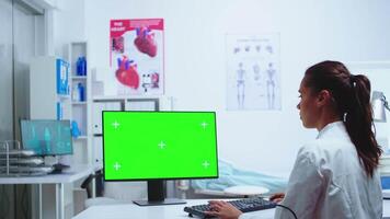 Medizin Schreiben diagnostizieren auf Computer mit Grün Bildschirm Monitor während Krankenschwester ist nehmen Anmerkungen im das Hintergrund. Computer mit austauschbar Bildschirm benutzt durch Medizin Spezialist im Krankenhaus und tragen Uniform. video