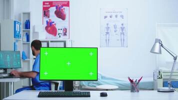 Doctor and her assistant checking patient x-ray and computer with green display in hospital. Desktop with replaceable screen in medical clinic while doctor is checking patient radiography for diagnose. video