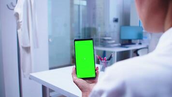 medicinsk läkare ser på telefon med grön skärm i sjukhus skåp och sjuksköterska få ut av hiss. sjukvård specialist i sjukhus skåp använder sig av smartphone med mockup. video