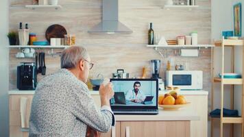 Senior couple during video conference with doctor using laptop in kitchen discussing about health problems. Online health consultation for elderly people drugs ilness advice on symptoms, physician telemedicine webcam. Medical care internet chat
