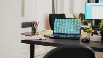 Laptop in company office shows stock exchange values changing in real time, panning shot. Paperwork on desk next to notebook showing forex trading indexes and pie charts graphs video