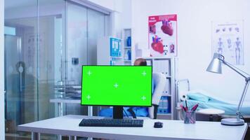 Chroma key on computer in hospital cabinet with medical personnel in the background. Computer with blank and copy space available on display of medicine specialist in clinic cabinet. video