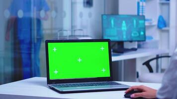 gezondheidszorg beoefenaar gebruik makend van laptop met groen scherm in ziekenhuis kamer. geneeskunde verpleegster binnengaan kliniek kastje. video