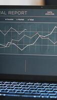 vertikal video företag diagram och siffror på bärbar dator vänster öppen på skrivbord i tömma arbetsplats, stänga upp. finansiell årlig Rapportera diagram på anteckningsbok skärm i företag bokföring avdelning kontor, panorering skott