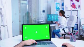 Pov laptop display with green mockup in hospital cabinet. Medical practitioner opening clinic glass door. Medic using notebook with chroma key on display in medical clinic. video