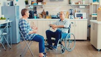 Happy senior woman talking with handicapped husband in wheelchair. Old woman having a conversation with husband. Living with disabled person with walking disabilities video