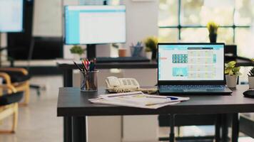 Stock market diagrams with charts and stock figures on laptop sitting on desk in empty workplace. Forex investment listings displayed on notebook screen in financial department, panning shot video