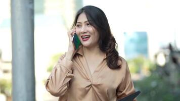 Teenager Asian woman feeling happy smiling and looking to camera while relax at outdoor city space. Portrait of successful business woman showing OK hand and wave up hand. Happy feeling concept. video