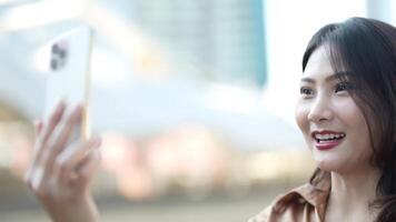 retrato do feliz o negócio mulher usa Smartphone dentro a ao ar livre com a cidade espaço fundo. tecnologia comunicação para estilo de vida e negócios. video