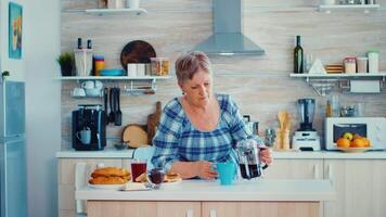 mogna kvinna i kök under frukost häller kaffe från franska Tryck. äldre person i de morgon- njuter färsk brun Kafé espresso kopp koffein från årgång mugg, filtrera koppla av förfriskning video