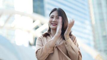 Teenager Asian woman feeling happy smiling and looking to camera while relax at outdoor city space. Portrait of successful business woman showing OK hand and wave up hand. Happy feeling concept. video