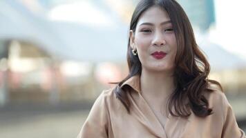 Teenager Asian woman feeling happy smiling and looking to camera while relax at outdoor city space. Portrait of successful business woman showing OK hand and wave up hand. Happy feeling concept. video