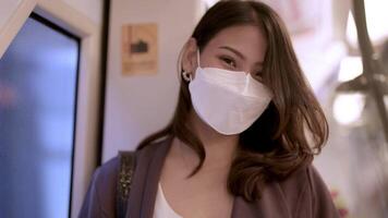 Aziatisch bedrijf vrouw vervelend gezicht masker terwijl op reis in massa doorvoer trein. vrouw is aan het kijken iets Aan slim telefoon met terwijl staand Bij venster. bescherming voor epidemie en Gezondheid in openbaar. video