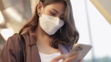 asiatisch Geschäft Frau tragen Gesicht Maske während Reisen im Masse Transit Zug. weiblich ist Aufpassen etwas auf Clever Telefon mit während Stehen beim Fenster. Schutz zum Epidemie und Gesundheit im öffentlich. video