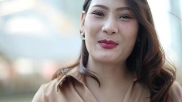 Teenager Asian woman feeling happy smiling and looking to camera while relax at outdoor city space. Portrait of successful business woman showing OK hand and wave up hand. Happy feeling concept. video