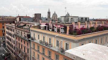 antenn se av parisian hustak och landmärken, en hög-vinkel se av färgrik byggnader, hustak Utsmyckad med rosa blommor, och historisk torn i de bakgrund, rom, Italien. video