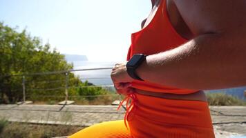 Close-up of chest area of an unrecognizable young woman. She zips her orange sport clothes before workout in park. Healthy lifestyle outdoors in nature, fitness concept. Slow motion. video