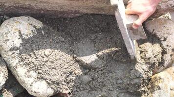 Construction, Worker Hands smooth wet cement in wooden frame at a construction site during daytime to ensure an even surface video