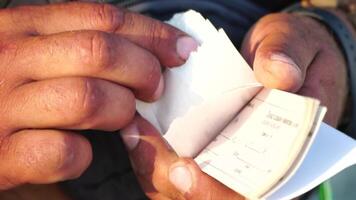 Close-up shot of a man's hands meticulously counting tickets. Slow motion video