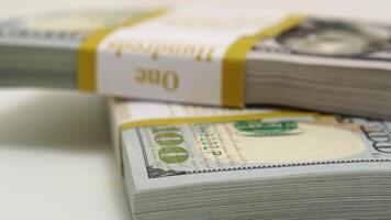 stack of bank bundles with US dollars on a white background. Close-up shot of new, freshly printed hundred-dollar bills rotating on a table. cash flow, business investment, or big money concepts. video