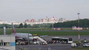 SAINT PETERSBURG, RUSSIA - JULY 26, 2022. Passengers boarding the Sukhoi Superjet of Rossiya plane at Pulkovo airport, long shot video