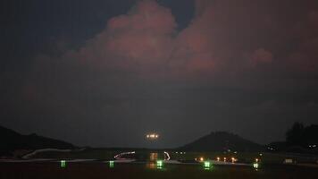 Airplane landing in the evening, long shot. Fiery sunset sky over the airport. Runway landing lights video