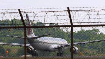 PHUKET, THAILAND - JANUARY 26, 2023. Airbus A330-302, A7-AEO of Qatar Airways starting, accelerating for takeoff at Phuket airport. Board behind the airport fence, rear view, medium shot video