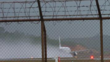 PHUKET, THAILAND - JANUARY 25, 2023. Airbus A320, HS-PPH of Bangkok Airways speed up before takeoff at Phuket airport, rear view. Airplane accelerating on a wet runway with water spray video