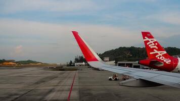 PHUKET, THAILAND - JANUARY 21, 2023. Passenger airplane of Thai AirAsia on apron at Phuket Airport. Porthole view of the apron video