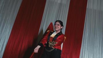 Stylish woman in a red jacket posing with confidence under warm stage lighting. video