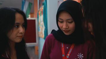 Three students in uniforms engaged in a lively discussion with books in hand in a school corridor. video