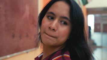 Portrait of a thoughtful young woman in an indoor setting, looking over her shoulder with a serious expression. video