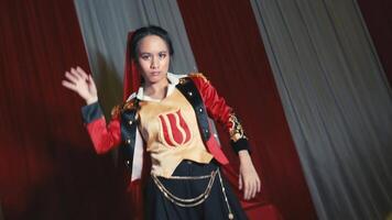 Performer in vibrant costume descending red stairs on stage with dramatic lighting and curtains in background. video