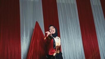 Smiling woman in jester costume performing on stage with red curtains in the background. video