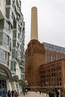 Modern residential building juxtaposed with a historic industrial chimney against a cloudy sky. photo